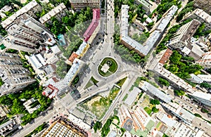 Aerial city view with crossroads and roads, houses, buildings, parks and parking lots. Sunny summer panoramic image