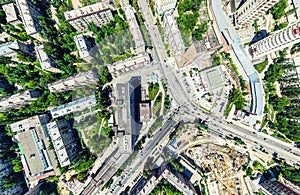 Aerial city view with crossroads and roads, houses, buildings, parks and parking lots. Sunny summer panoramic image