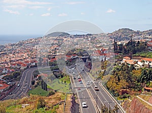 an aerial cityscape view of funchal showing traffic on the main VR1 motorway running into the city with the coast visible in the