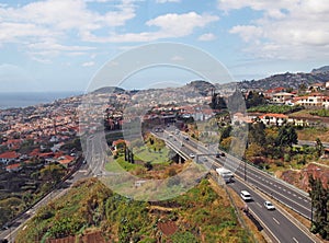 an aerial cityscape view of funchal showing traffic on the main VR1 motorway running into the city with the coast visible in the