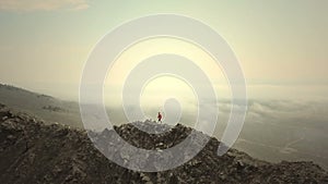 Aerial close up - Female hiker proudly standing on mountain top on a cold, cloudy day in autumn.