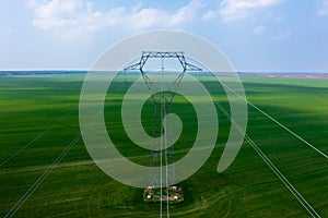 Aerial close-up view of electricity pylon with power lines over agricultural field