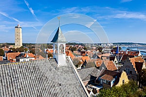 Aerial close up of Westerkerk church bell tower with rooster weather vane in West-Terschelling, Netherlands. Brandaris lighthouse.