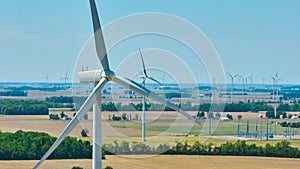 Aerial close up of wind turbine with wind farm in background and substation