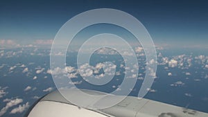 Aerial of clouds over the sea with blue sky from inside an airplane
