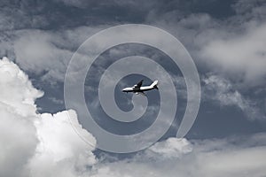 Aerial concept on a blue sky among white clouds and sunlight a passenger or cargo plane is flying