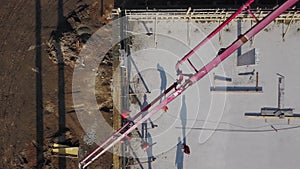 Aerial of concrete boom pump crane arm truck with outriggers pouring building mixture into a formwork. Construction
