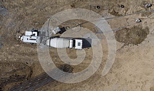 Aerial. Concrete mixer truck delivers concrete through a long hose. Top view