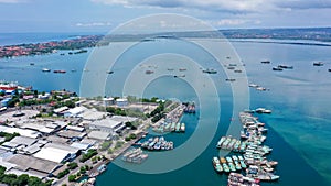 Aerial container terminal of Benoa Harbour with stacks of the boxes and a red command tower under light blue sky