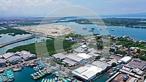 Aerial container terminal of Benoa Harbour with stacks of the boxes and a red command tower under light blue sky