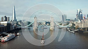 Aerial daytime view to the lifted Tower Bridge and yacht going through it.