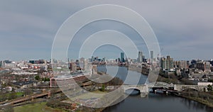 Aerial descending footage of bridge over Charles river and buildings on waterfronts. Downtown skyscrapers in distance