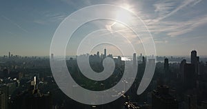 Aerial descending footage of cityscape against sunshine. Hazy skyline with downtown skyscrapers. Manhattan, New York