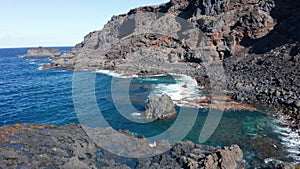 Aerial dolly from fishing village over ocean coast and hardened lava