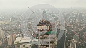 Aerial dolly shot tilting into overhead of tall skyscraper under construction in urban city center