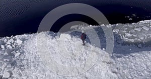 Aerial dron view of young active happy man staying on the ice glaciers near coastline of winter sea. Drone view