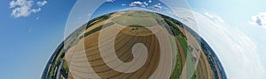 Aerial drone 180 degree arch view on harvester unloading seed to tractor trailer, agricultural landscape