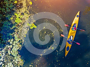 Aerial drone bird`s eye view photo of two kids enjoying kayak ride on beautiful river. Little boy and teenager girl