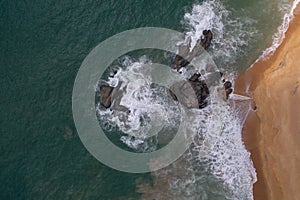 Aerial drone bird view shot of the sea shore with turquoise blue water, large white waves and foam, empty beach with yellow sand,