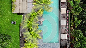 Aerial Drone Flight top down View of slim young woman in beige bikini and straw hat relaxing near luxury swimming pool