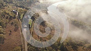 Aerial drone flight view over low clouds and morning mist covered mountain slopes at sunrise. Sunrise in mountains