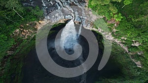 Aerial drone flying back and tilt revealing Coban Sriti waterfall, Indonesia