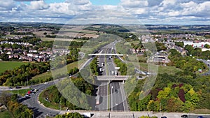 Aerial drone footage of the busy M1 motorway with three bridges crossing over the highway, filmed in the village of Barnsley in