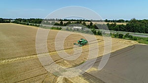 Aerial drone footage. Flight over a wheat field with harvestaer along the highway