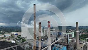 Aerial drone footage of a large coal power plant station with cooling towers chimney and boiler house in an air