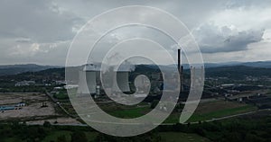 Aerial drone footage of a large coal power plant station with cooling towers chimney and boiler house in an air
