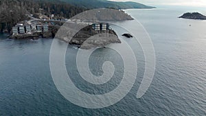 Aerial drone footage of the rugged Vancouver Island coastline near Sooke with a modern condo development atop a ocean