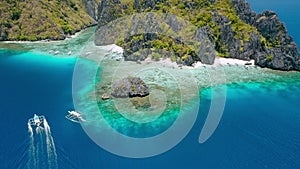 Aerial drone footage of tourist banca boat approaching Shimizu Island beach in El Nido, Palawan, Philippines. Rocks and