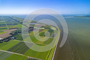 Aerial drone image of typical Dutch farmland, polder, near lake and windmills