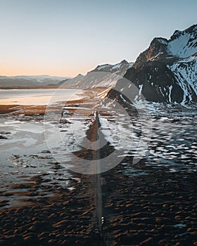 Aerial drone panorama of gravel road at sunset with Vestrahorn mountain and stokksnes beach in Iceland in the background