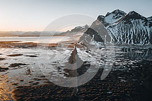 Aerial drone panorama of gravel road at sunset with Vestrahorn mountain and stokksnes beach in Iceland in the background
