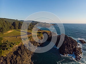 Aerial drone panoramic view of rocks in the ocean. Rocky coast with green plants. Ocean waves. Amazing natural landscape. Top view