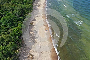 Aerial drone perspective view on beautiful and silent paradise place with forest, clean sand beach and turquoise sea waves. People