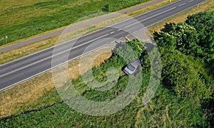 Aerial drone perspective view on car accident hitting the bushes and roadside, high speed on curve causing the car to fell of the