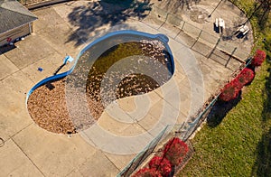 Aerial drone photo of an uncovered swimming pool filled with fallen autumn leaves