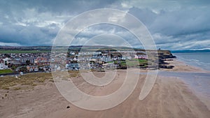 Aerial drone picturesque panorama of sandy beach at Castlerock, Northern Ireland on cloudy spring day. Dark clouds, wind and low