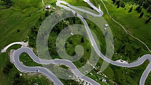 Aerial drone shot from above the winding mountain road, Dolomites, Italy. Cloudy weather in late summer. Cars driving