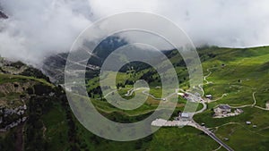 Aerial drone shot from above the winding mountain road, Dolomites, Italy. Cloudy weather in late summer. Cars driving