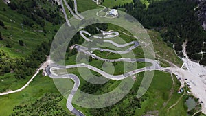 Aerial drone shot from above the winding mountain road, Dolomites, Italy. Cloudy weather in late summer. Cars driving