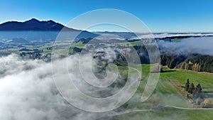 Aerial drone shot of AllgÃ¤u landscape with road in autumn with fog