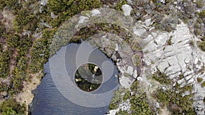 Aerial drone shot of big sinkhole constructed as water spillway at Covao dos Conchos dam lake in Serra da Estrela