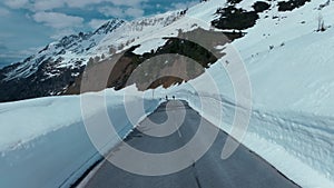 Aerial drone shot cyclists on snow mountain road