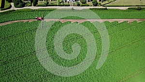 Aerial drone shot of farm machinery spraying agriculture fields in the Suffolk countryside before they harvest