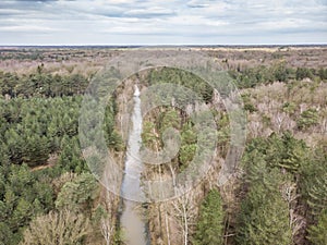 Aerial drone shot, of a forest with river or canal running through in early spring