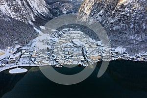 Aerial drone shot of Lahn village covered by snow by Hallstatt lake in Austria during winter