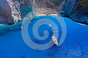 Aerial drone shot of luxury yacht leaving Zakynthos shipwreck navagio beach in summer